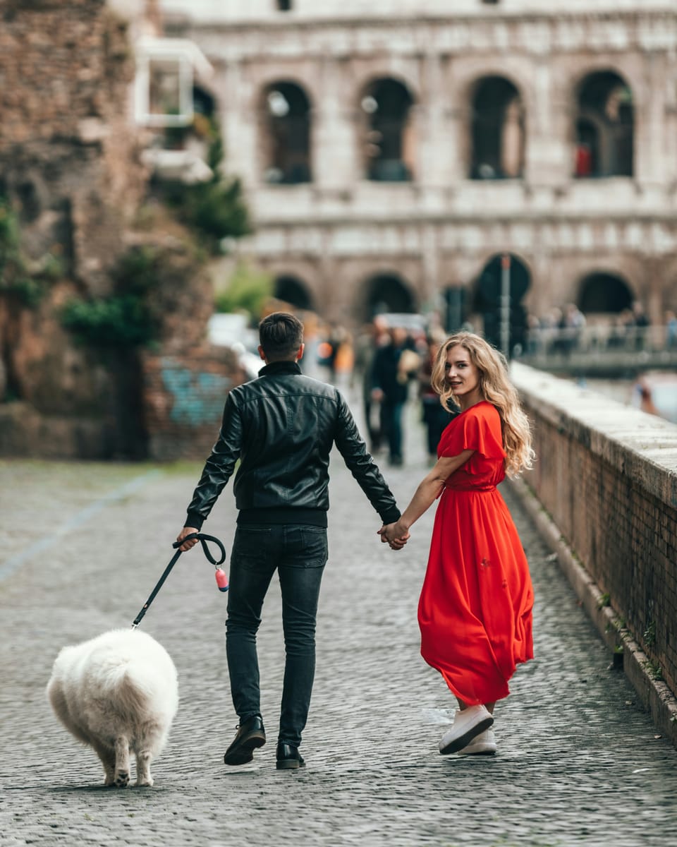 A couple holding hands on a walk with their Samoyed